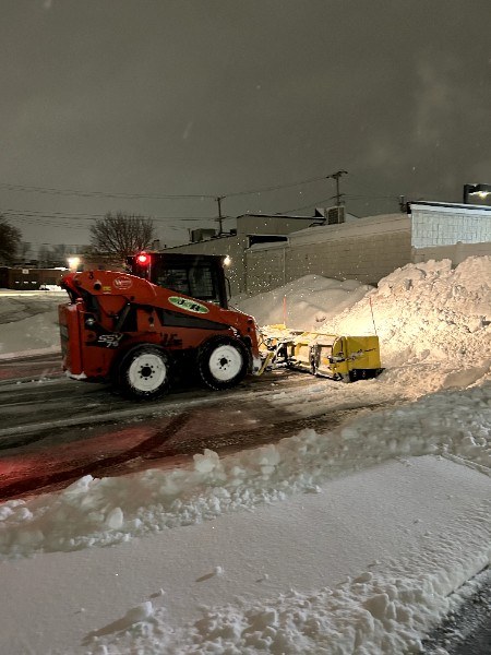 J and R skid steer pushing snow banks during a night storm